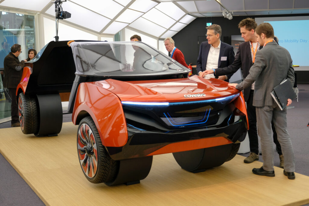 Mehrere Personen betrachten ein Exponat in Form einer futuristischen Auto-Karosserie beim Covestro Mobility Day 2018.
